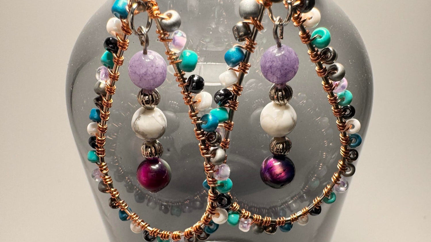 Celestial Tears earrings hanging from an opaque vase displaying the crystal energies and cosmic allure