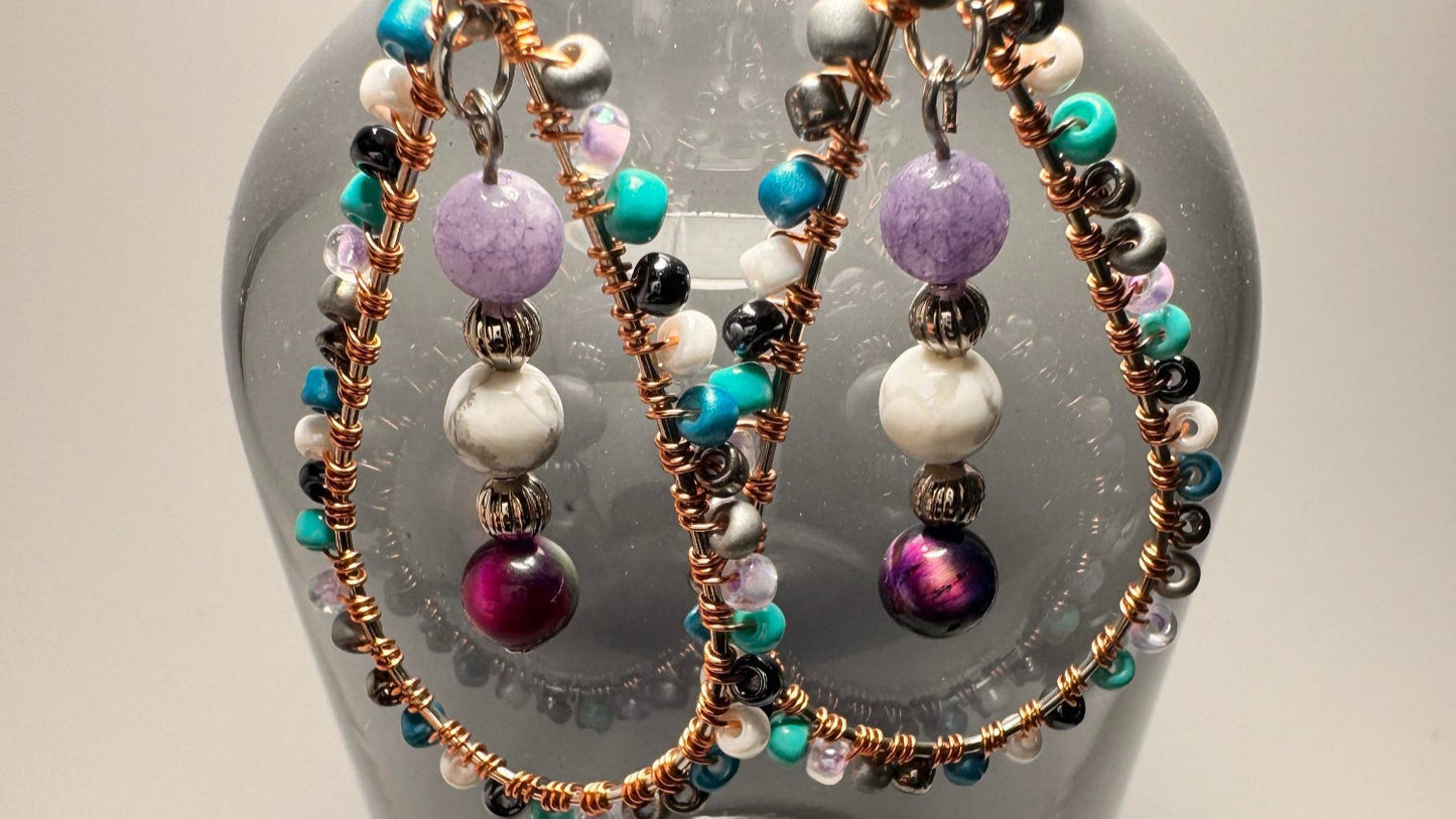 Celestial Tears earrings hanging from an opaque vase displaying the crystal energies and cosmic allure