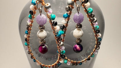 Celestial Tears earrings hanging from an opaque vase displaying the crystal energies and cosmic allure