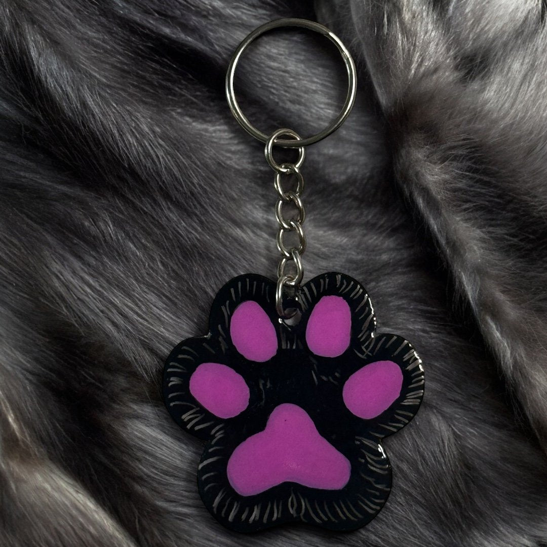 paw shaped keychain with black background that has been scratched to give the effect of fur. 