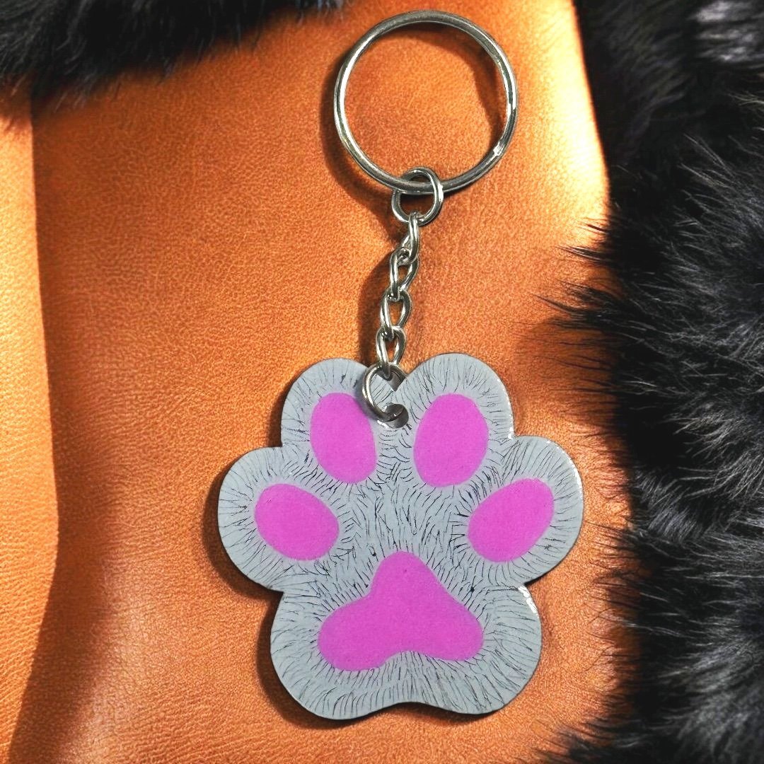 paw shaped keychain with gray background that has been scratched to give the effect of fur. 