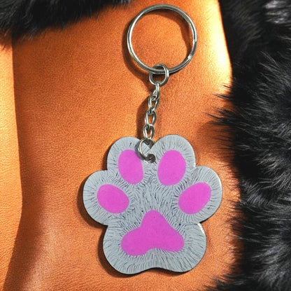 paw shaped keychain with gray background that has been scratched to give the effect of fur. 