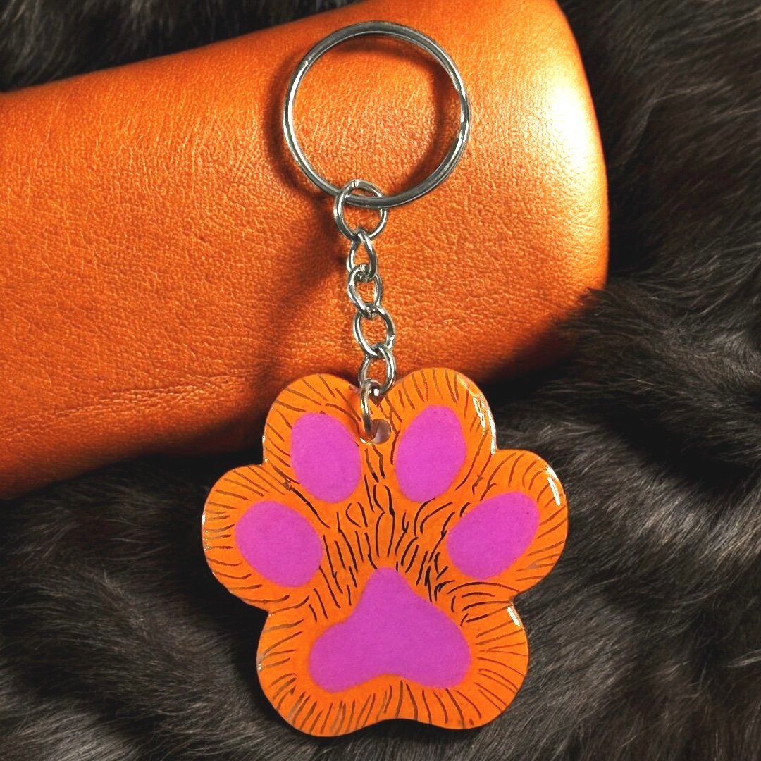 paw shaped keychain with orange background that has been scratched to give the effect of fur. 