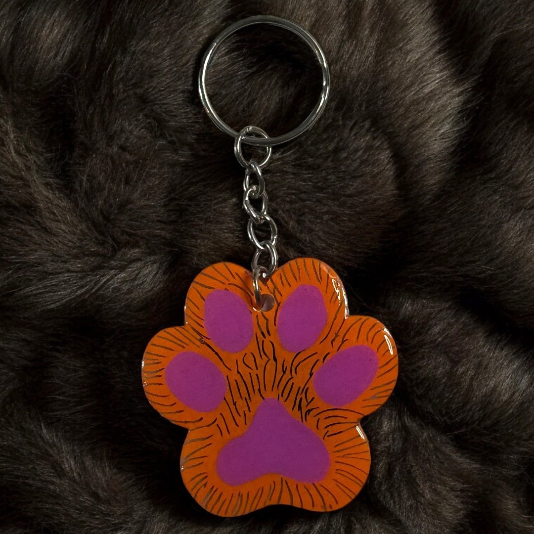 paw shaped keychain with orange background that has been scratched to give the effect of fur. 