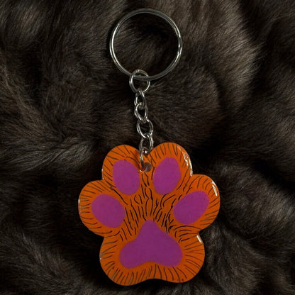 paw shaped keychain with orange background that has been scratched to give the effect of fur. 