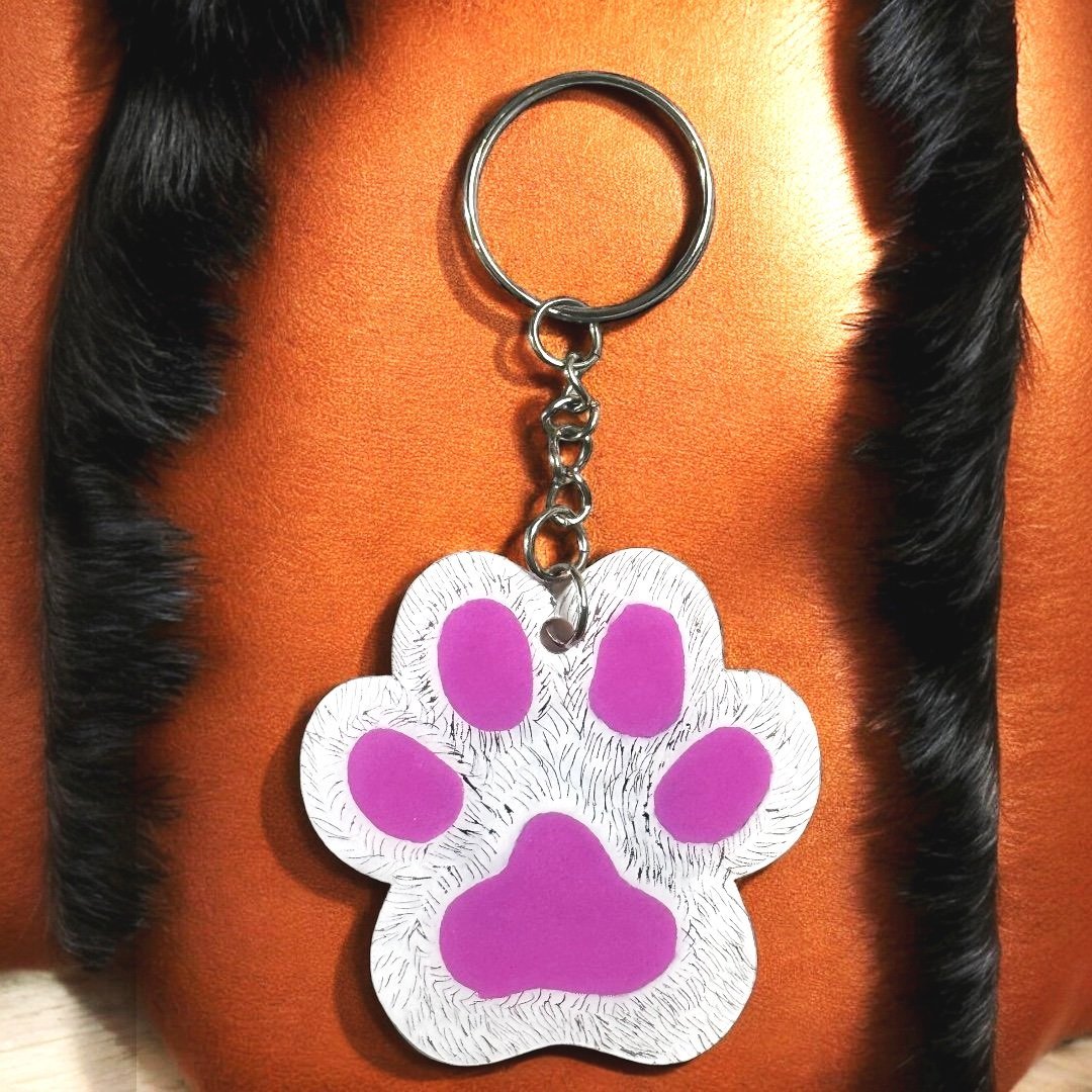 paw shaped keychain with white background that has been scratched to give the effect of fur. 