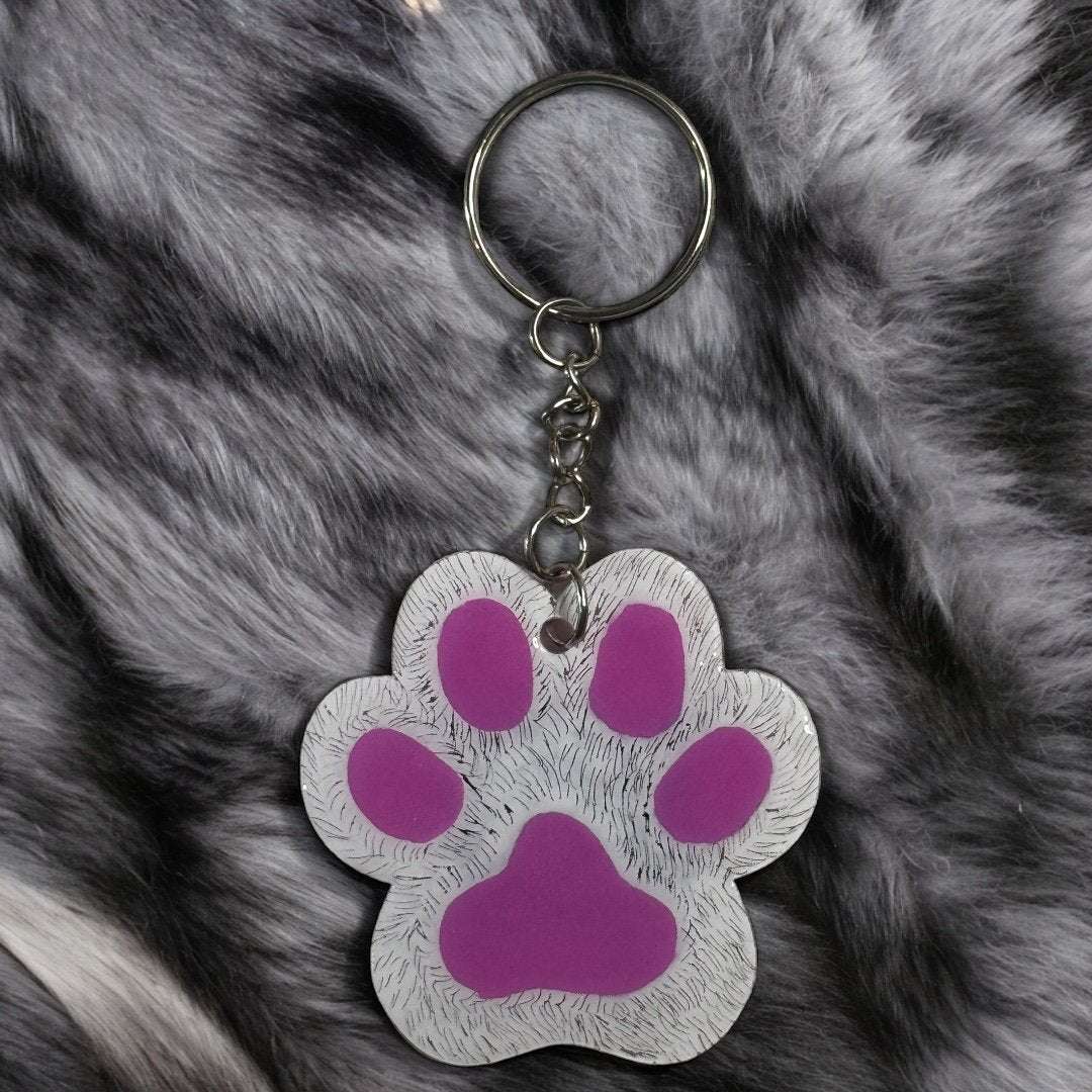 paw shaped keychain with white background that has been scratched to give the effect of fur. 