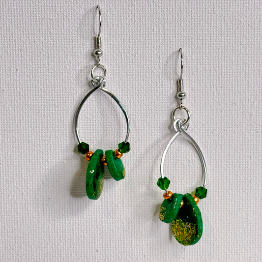 Emerald Essence dangle earrings with hammered wire loops, vibrant green polymer clay, and sparkling glass beads. Handmade statement earrings perfect for adding a touch of elegance and style.