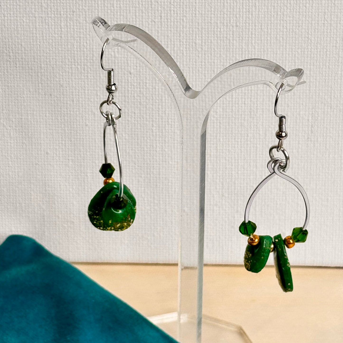 Emerald Essence dangle earrings with hammered wire loops, vibrant green polymer clay, and sparkling glass beads. Handmade statement earrings perfect for adding a touch of elegance and style.