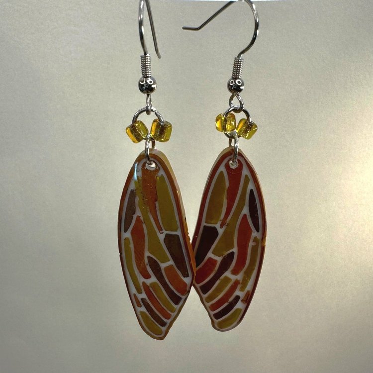 Resin formed earrings colored in copper, gold, and metallic brown resemble the wings of a cicada