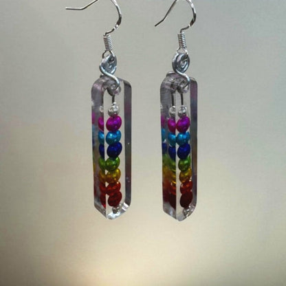 Rainbow colored shiny beads encased in resin making a rectangular dangle earring.