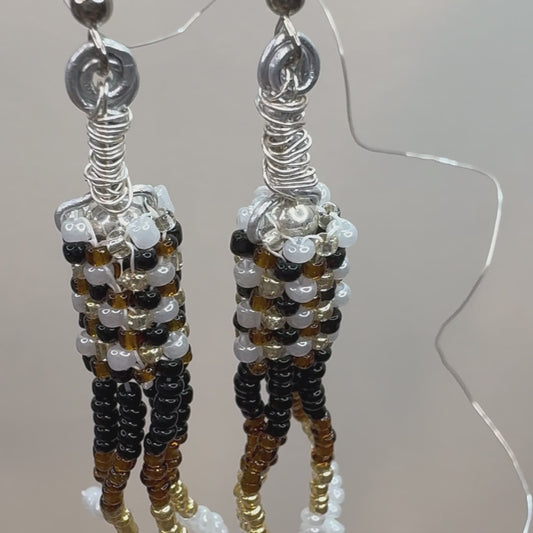 Brown, Black, White, and Gold beads woven together form a cylinder and have stacks of beads hanging down, making a chandelier style earring.